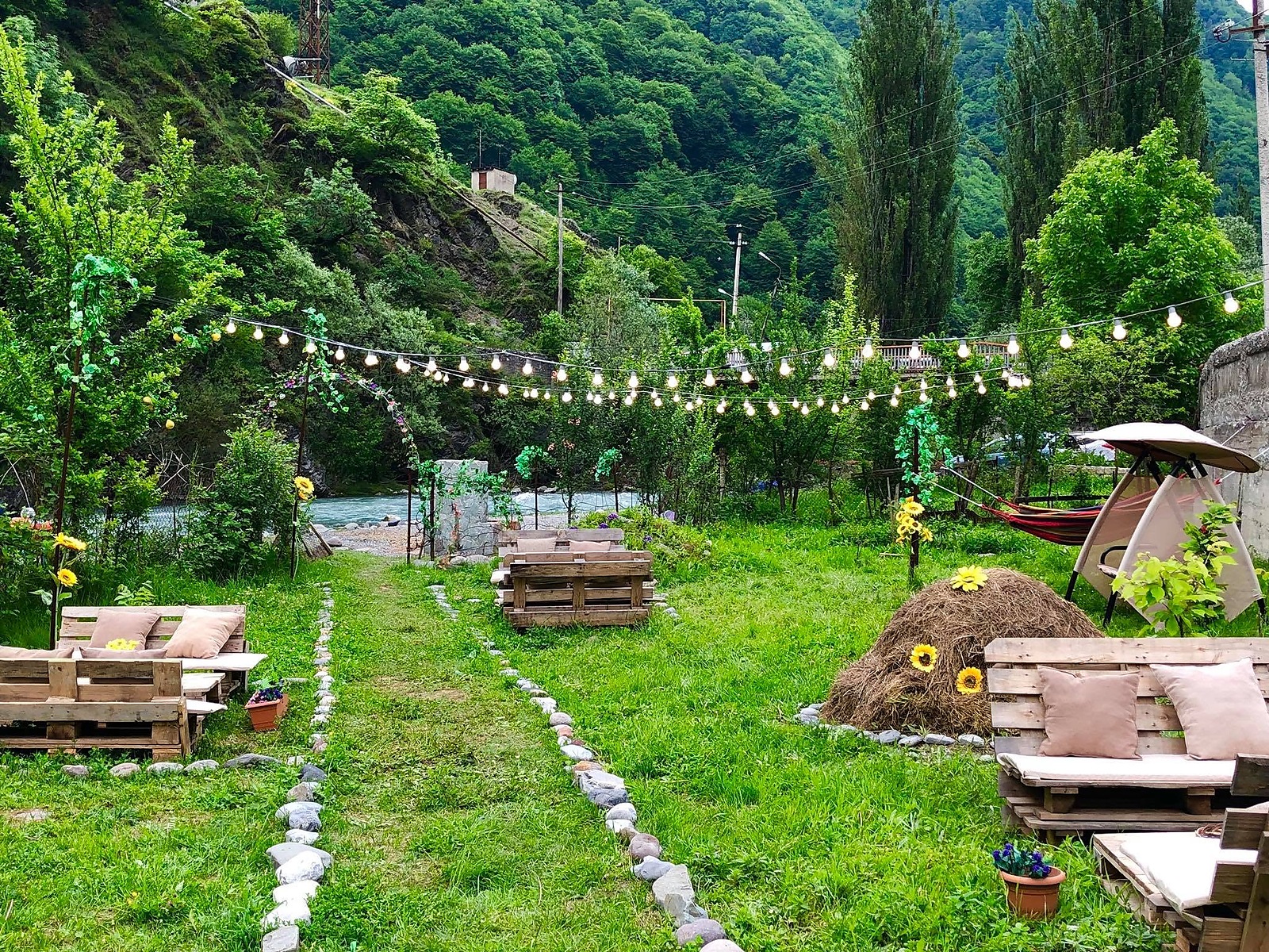 Riverside garden with festoon lights, pallet seating and hammocks
