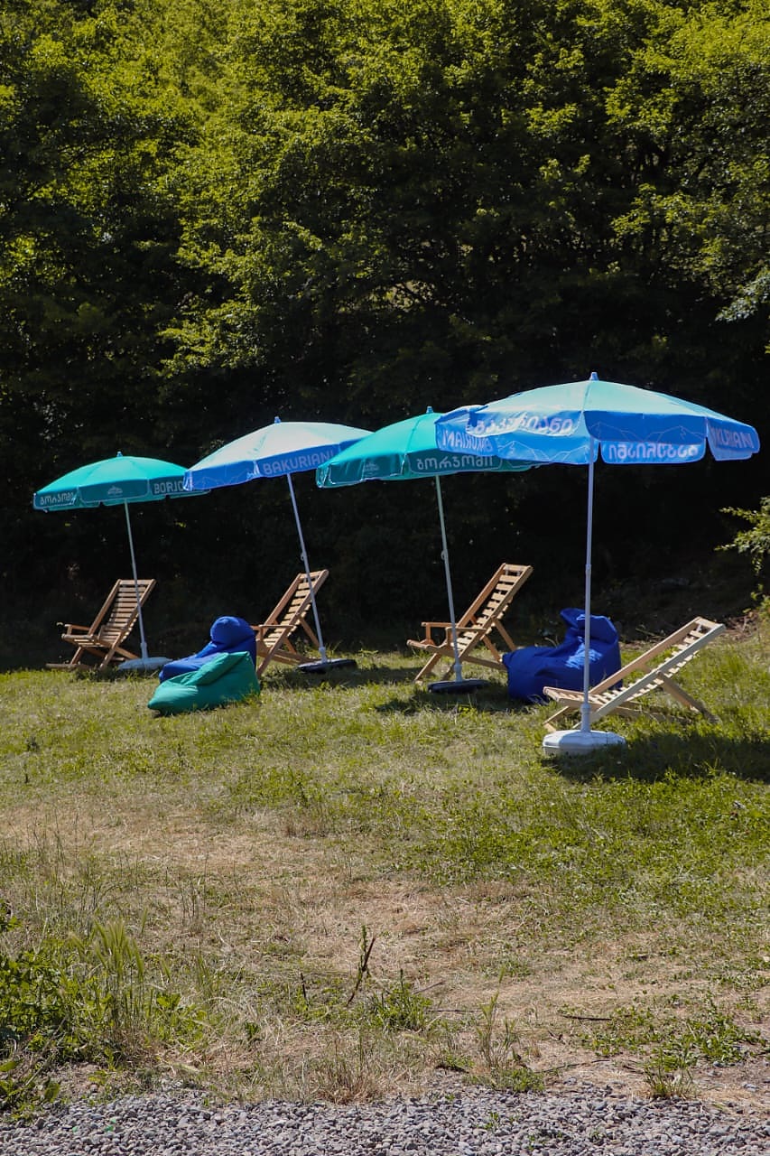 Sun loungers and parasols set up on the grass beside the river